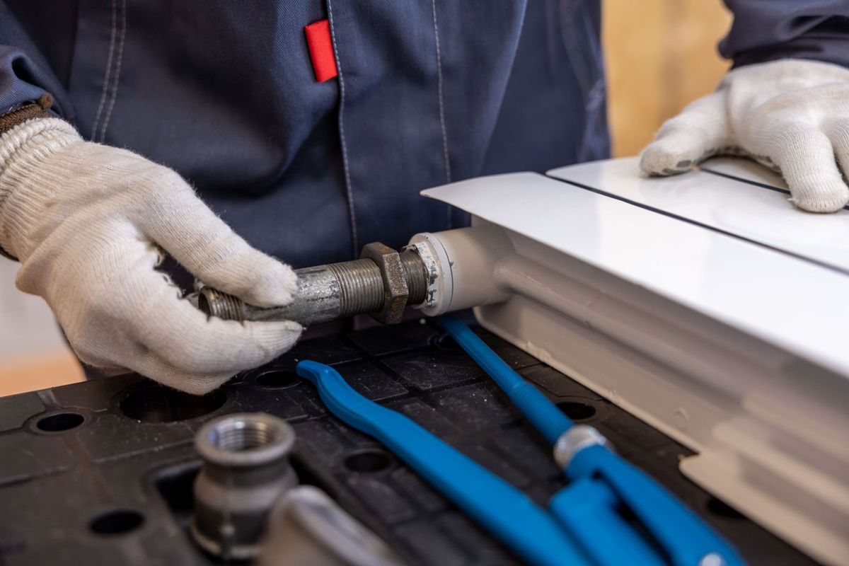 An engineer connecting pipework to a radiator